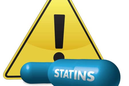 Statin pill with warning symbol, symbolizing role in managing hyperlipidemia