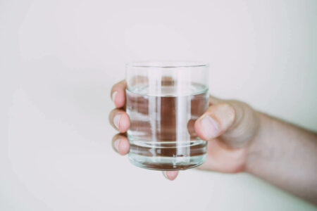 Hand holding a glass of water, representing a bedtime habit for preventing cerebral thrombosis