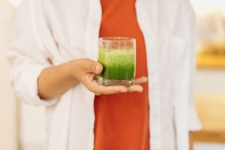 Person holding a clear glass of fresh smoothie, a healthy beverage for cardiovascular health