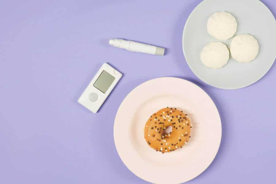 Glucometer and Insulin Pen Beside Plates of Donut and Steamed Buns - Blood Sugar Control Concept