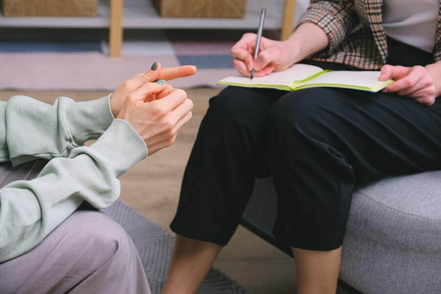 Anonymous female therapist and client discussing health diagnosis and prevention strategies during a session in a modern office.