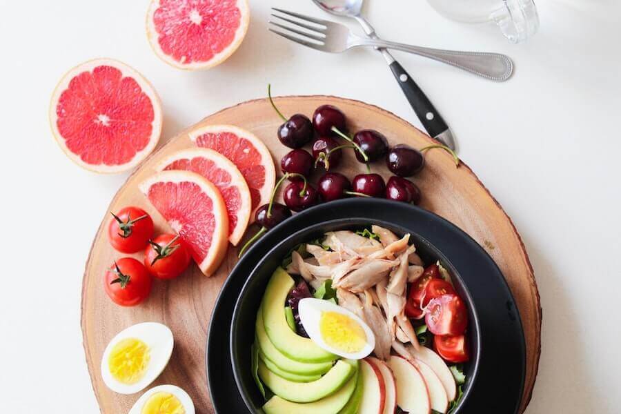 A colorful bowl of vegetable salad and sliced fruits, representing a healthy diet for brain health.
