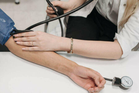 Medical practitioner monitoring blood pressure of a patient during a medical examination.