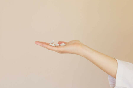 Female pharmacist holding a pile of white pills on her palm
